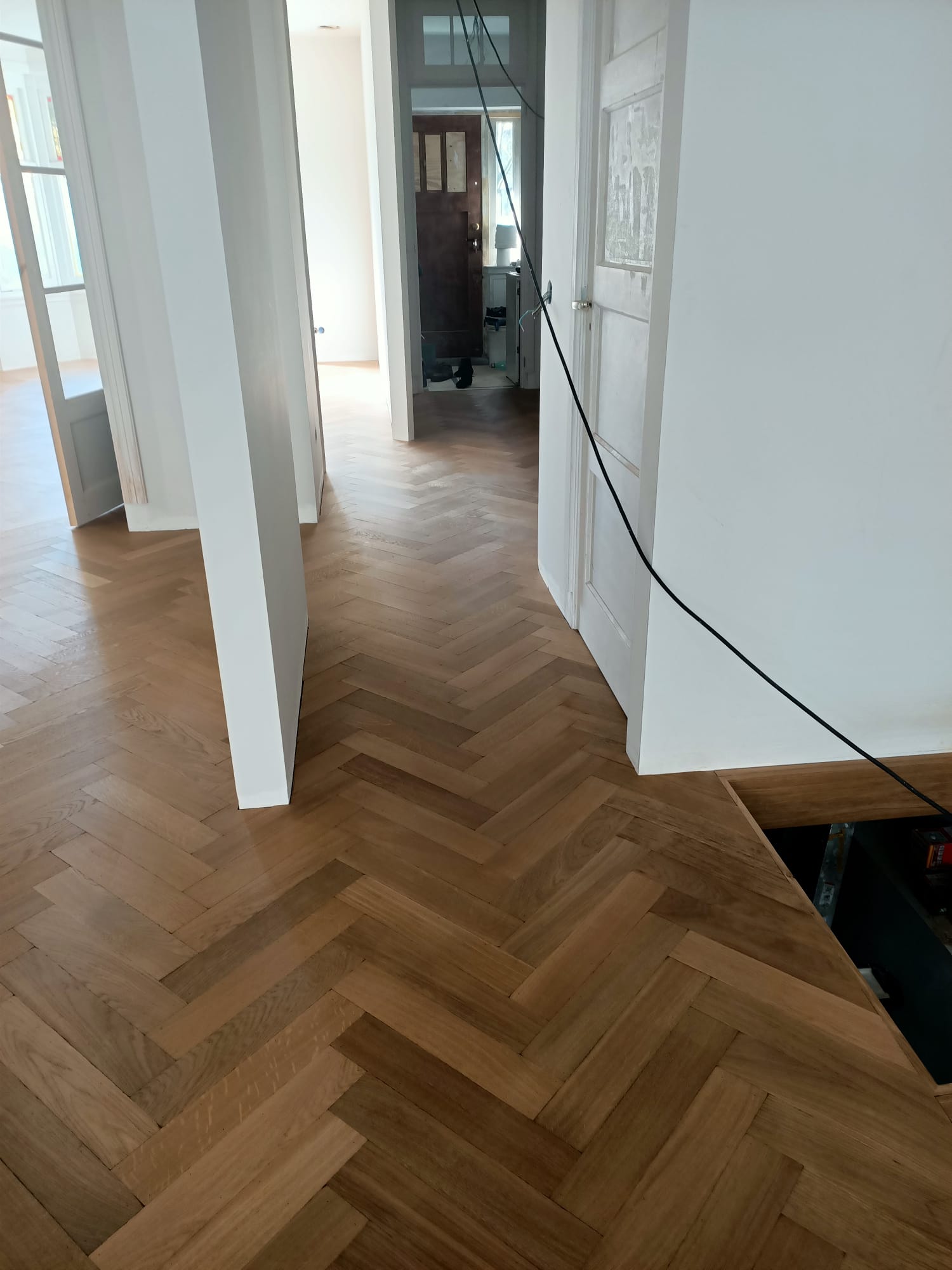 Ook in de hal is doorgelegd en de trap is ook bekleed met eiken op maat gemaakte overzettreden.
