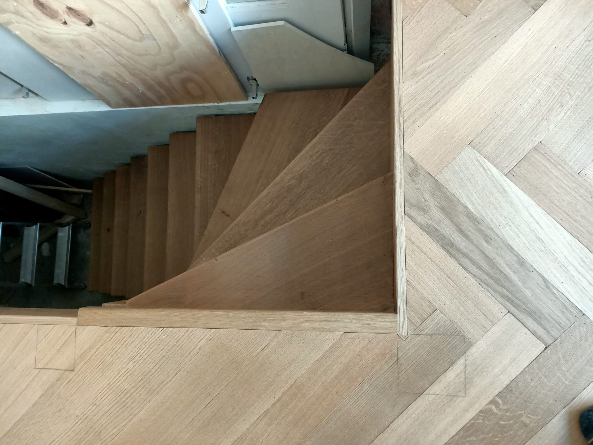 De trap is bekleed met op maat gemaakte overzettreden die ook gerookt en gelakt zijn.
