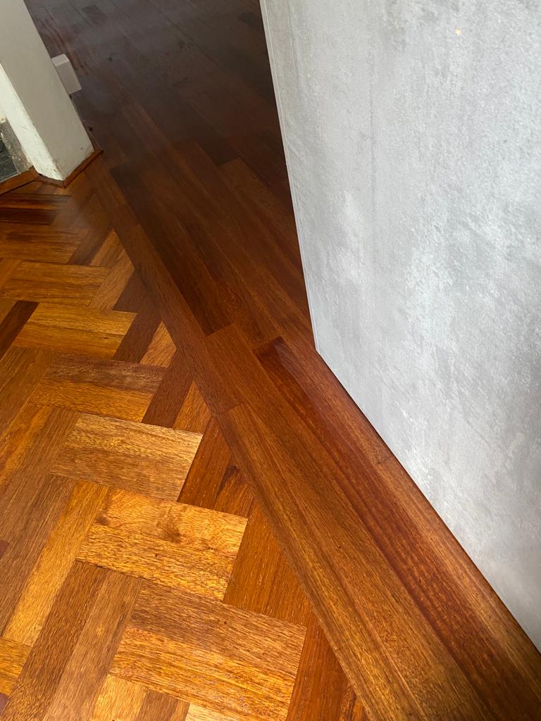 Een stukje recht gelegde afzelia tapis stroken is aangelegd een andere ruimte is.