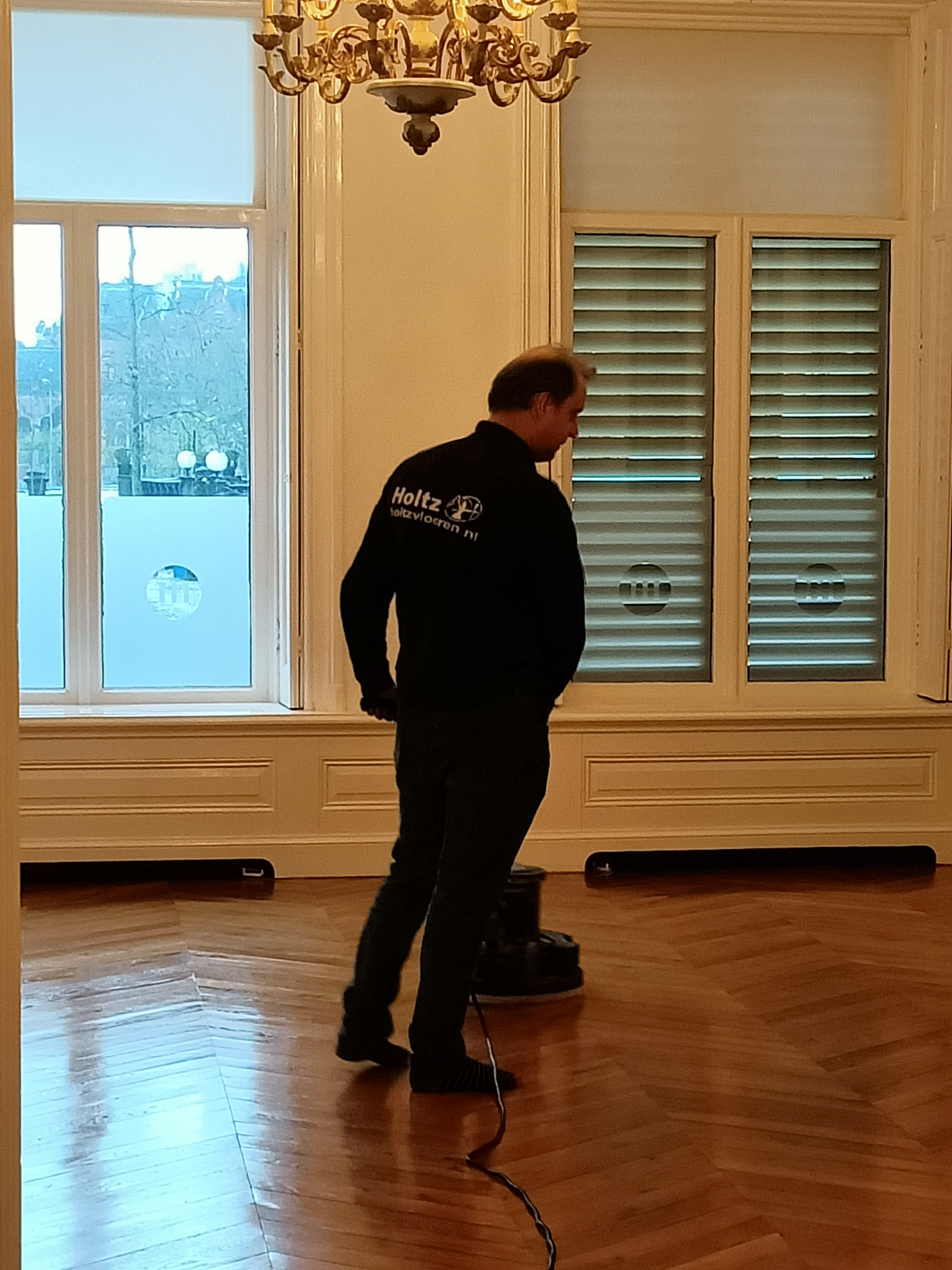 Holtz medewerker is bezig met de woodboy om de polish aan te brengen.