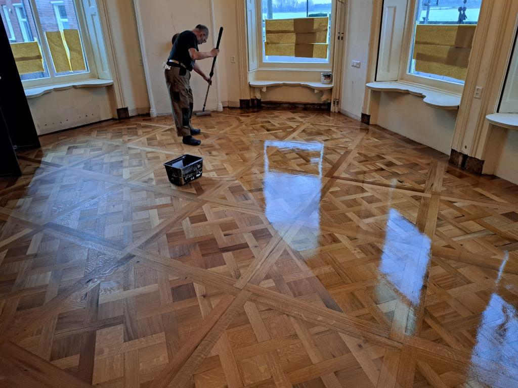 De versailles parket is net gelegd en wordt afgewerkt met een lak