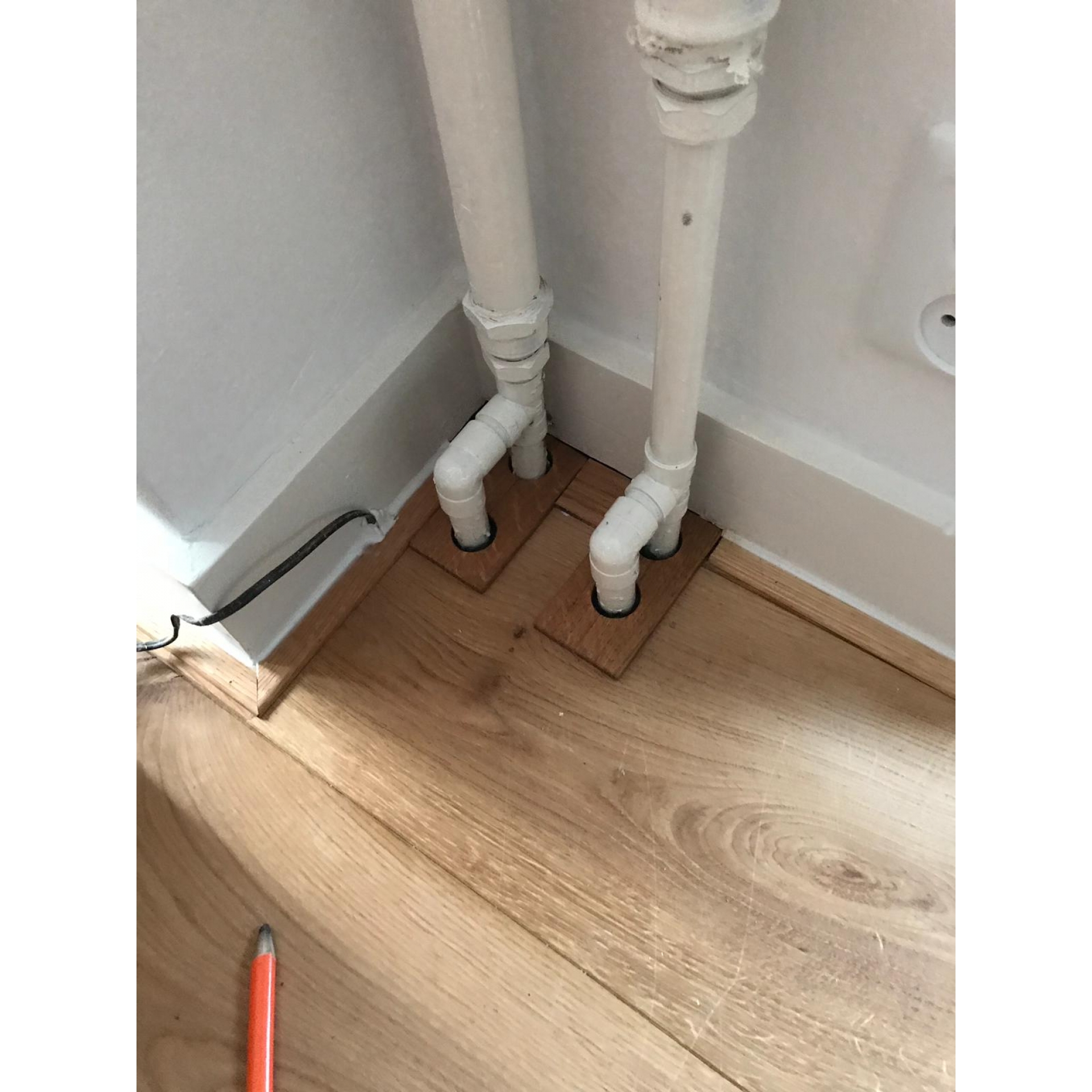 Eiken plint afwerking rond oude radiator buizen in Hoogezand