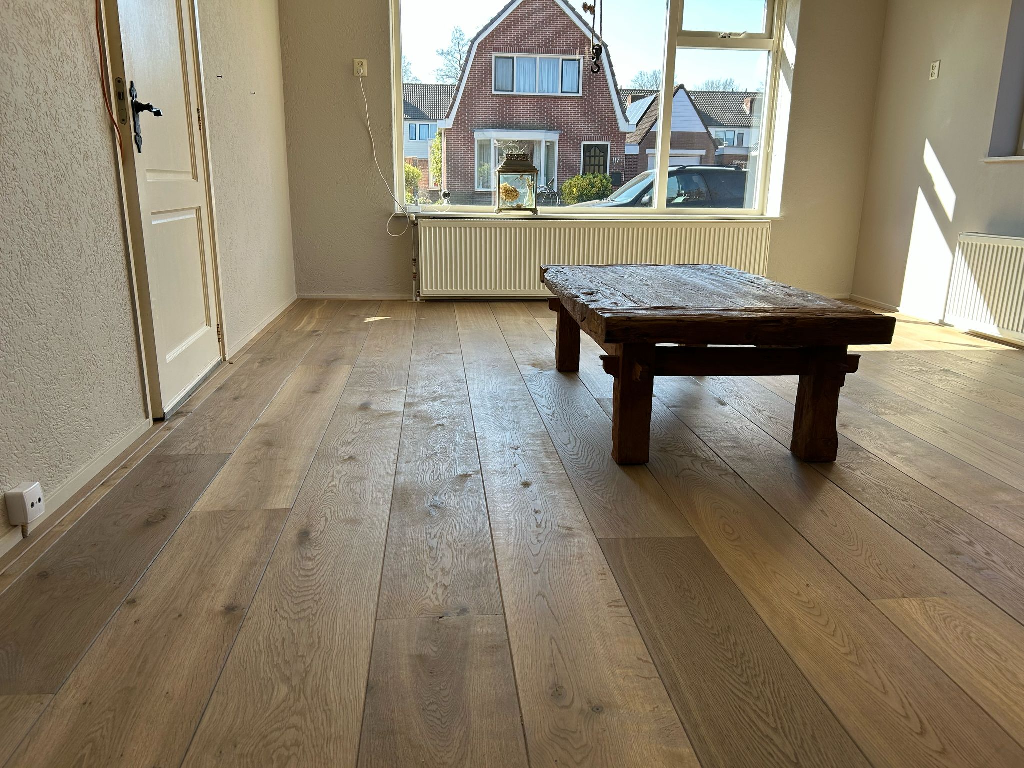 De eiken planken zijn in de lengte van de kamer gelegd in de woonkamer.