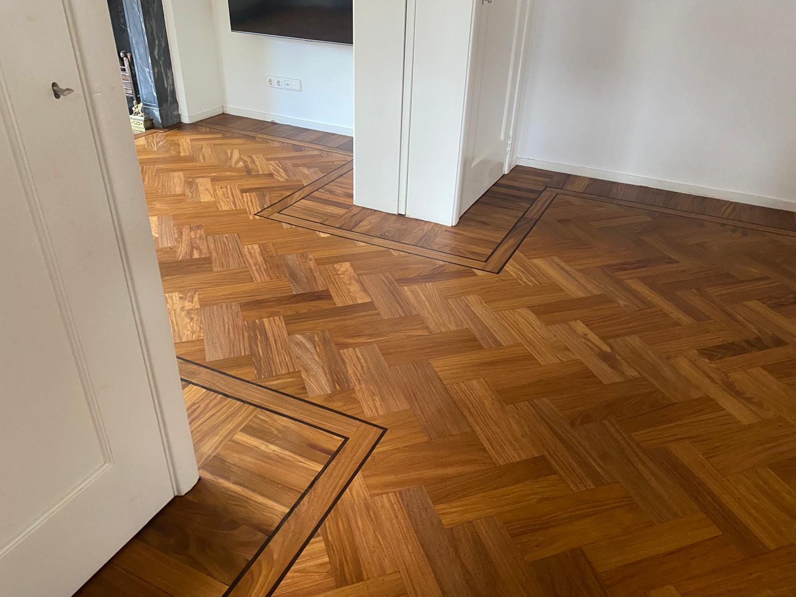 Afrormosia visgraatvloer, gelegd rond de suite deuren met band, dubbele bies en staande friesen.