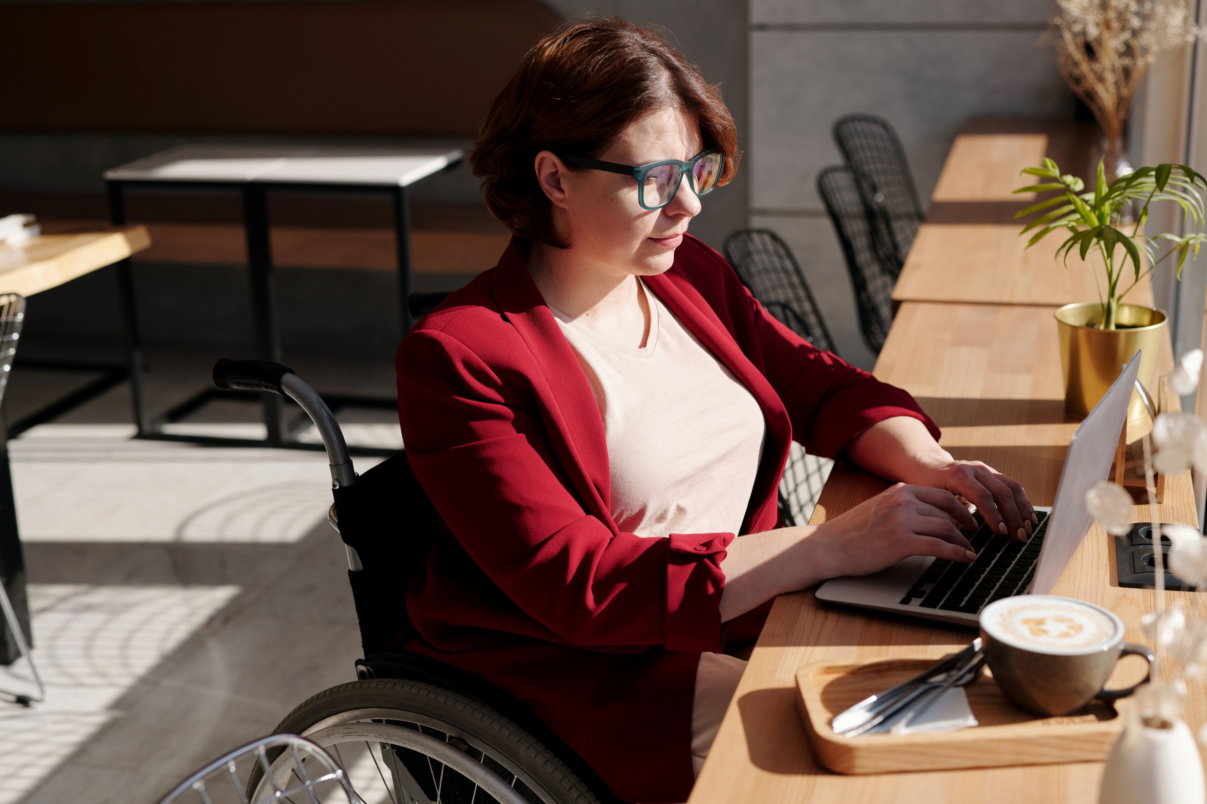 Vrouw in rolstoel achter de laptop